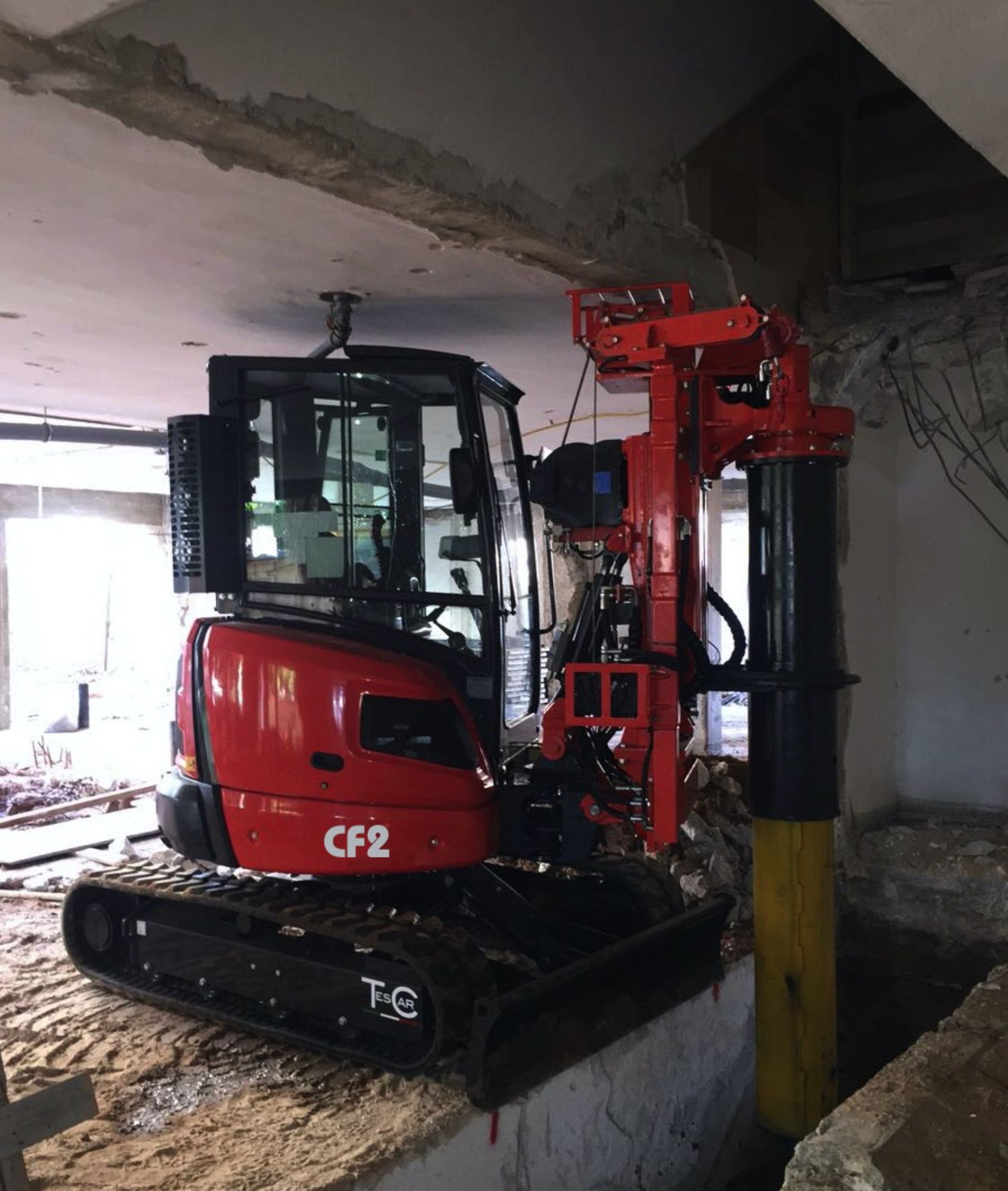 Compact tracked piling drill rig working under low headroom with casing installed