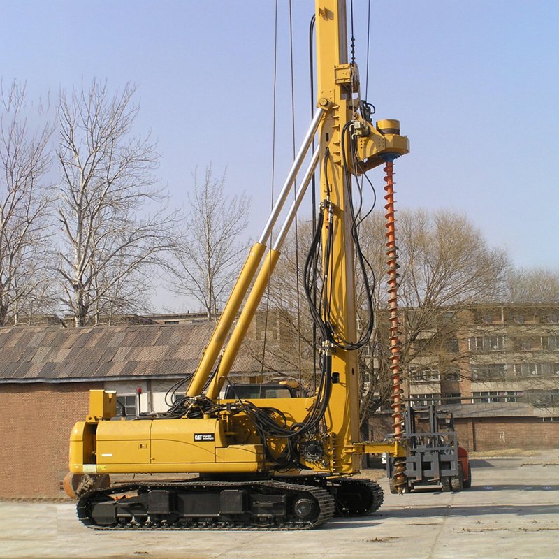 Hydraulic piling rig with mast and auger attachment on a construction site